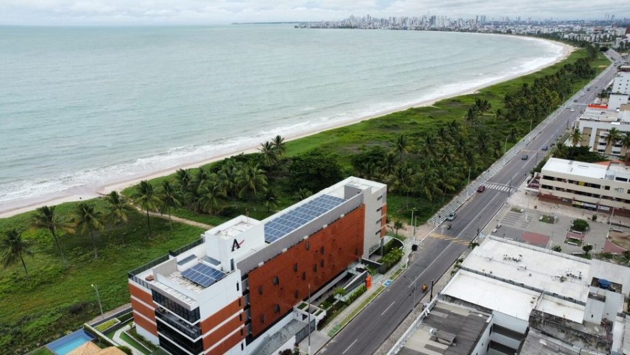 Vista aérea de condomínio residencial à beira-mar com sistema de energia solar na cobertura